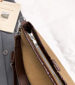 Detalle de cremallera metálica y textura de lona y cuero en el bolso de hombro informal