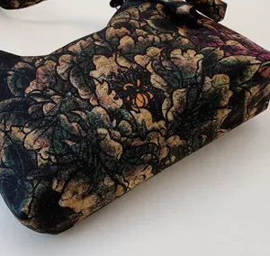 Detailed macro view of dark floral fabric texture and peony pattern on a crescent bag