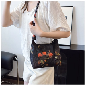 Close-up of semi-moon canvas bag with orange persimmon patterns and adjustable strap