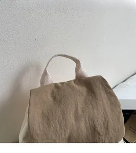 Close-up of textured brown canvas bag with soft woven handle and You Ji Bear rubber label