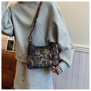 Detail of vintage floral print crescent bag shown as a crossbody on a model indoors