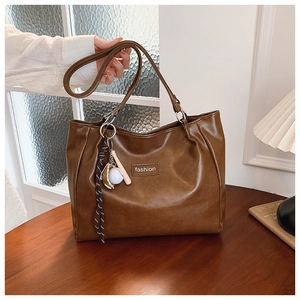Detailed view of brown faux leather tote with fashion logo and baseball charm