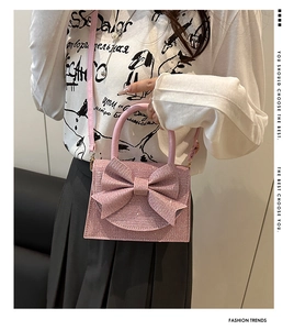 Dettaglio borsa di paillettes rosa con grande fiocco e tracolla indossata da una modella