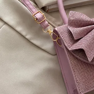 Close-up of light gold hardware and pink glitter fabric on the stylish bow handbag