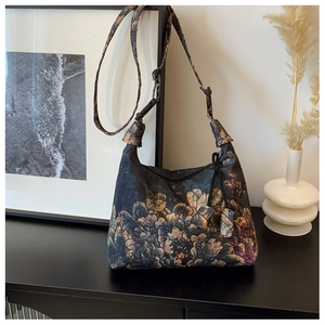 Detail of floral printed crescent bag with adjustable strap and buckle closure