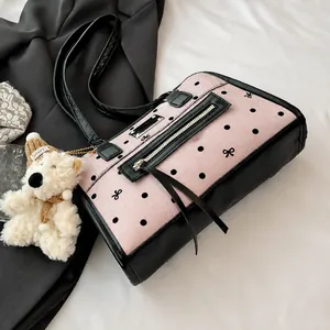 Details der rosa gepunkteten Canvas-Handtasche mit silbernen Beschlägen und Bär-Anhänger