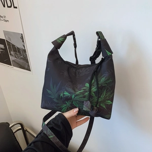 Black crescent bag with green leaf print, adjustable handle and detachable shoulder strap