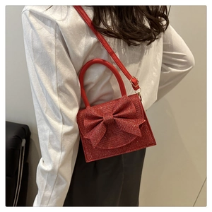 Dettaglio mini borsa rossa di paillettes con fiocco grande e tracolla sottile regolabile