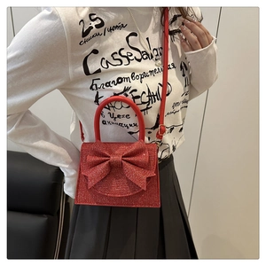 Dettaglio della borsa rossa glitterata con grande fiocco indossata da una modella