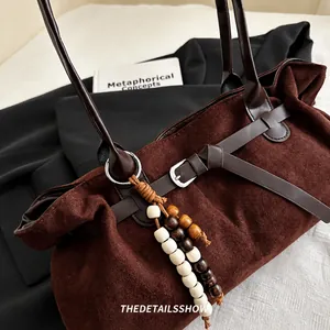 Nahaufnahme der dunkelbraunen Wildledertasche mit Lederriemen und Vintage-Perlenanhänger