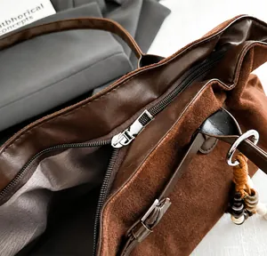 Detailansicht des glatten Reißverschlusses und der Wildledertextur der braunen Shopper