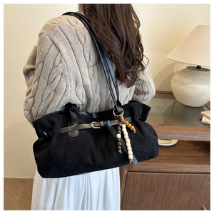 Detail der schwarzen Wildleder-Einkaufstasche mit Retro-Perlenanhänger und Metallakzent