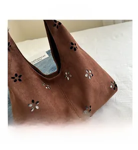 Detalle de flores cortadas con láser en bolso tote de gamuza marrón con forro plateado