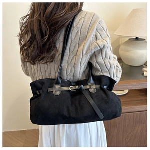Detail of black suede tote bag featuring decorative leather strap and metal buckle