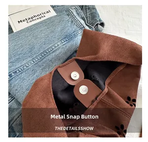 Detalle de bolso de ante marrón con diseño floral calado con láser y cierre magnético