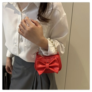 Detail van rode leren handtas met parelhandvat en elegante grote strikversiering