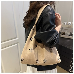 Detail of beige faux suede shoulder bag featuring laser-cut floral patterns and rhinestones