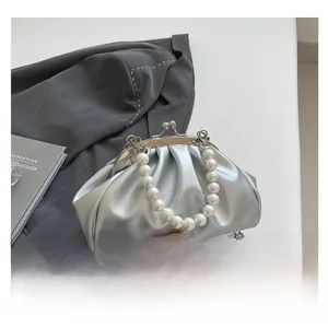 Detail of silver pleated cloud bag with pearl handle and metal chain strap