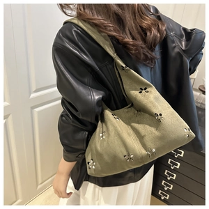 Detalle del patrón floral cortado con láser en un bolso de hombro verde oliva
