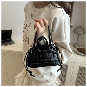Détail du sac à main noir motif crocodile avec cordon de serrage et lettrage mode