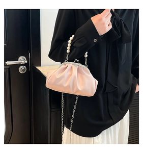 Detail van roze geplooide cloud bag met grote parel handgreep en metalen kettingriem