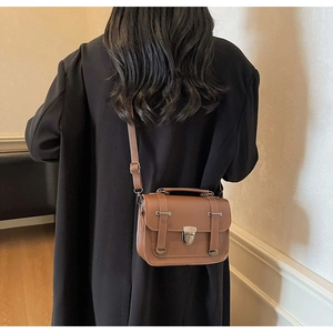 Vue détaillée arrière d'un sac bandoulière vintage en cuir marron porté par un modèle