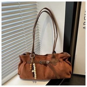 Detail of vintage brown suede tote bag with wooden bead tassel and buckle strap accents