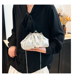 Detail of silver pleated cloud bag featuring large pearl handle and metal chain strap