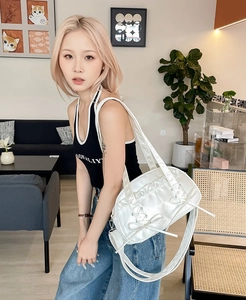 Detail of white patent leather shoulder bag featuring bow decor and pleated texture