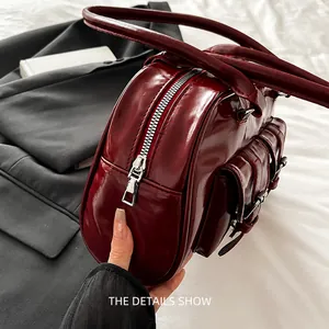 Macro shot of smooth silver zipper and glossy burgundy leather on a boston shoulder bag