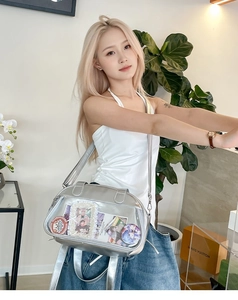 Silver ita bag with clear window showing anime badges and charms on a crossbody strap