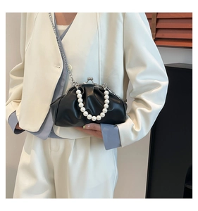 Detail van zwarte geplooide cloud bag met parel handvat en zilveren ketting