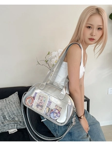 Detail of silver ita bag with transparent PVC window displaying anime badges and cards