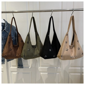 Detalle de bolsos tote de ante en varios colores con diseños de flores caladas en una puerta
