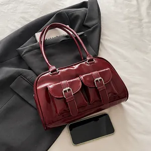 Detail of burgundy PU leather shoulder bag with dual buckle pockets on office suit backdrop