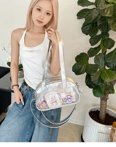 Silver Ita bag with transparent window showing anime badges on a casual shoulder strap