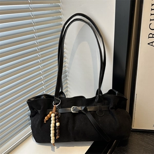 Retro black suede tote bag with wooden bead pendant and long shoulder strap in natural light