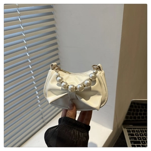 Chique crèmewitte handtas met een grote strik en een elegant parelmoeren handvat