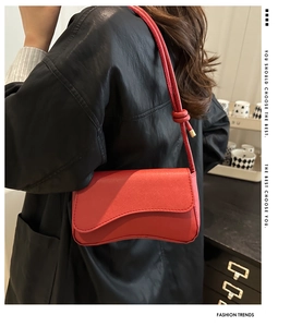 Rode crossbodytas met knoopdetail gedragen door een model in leren jasje