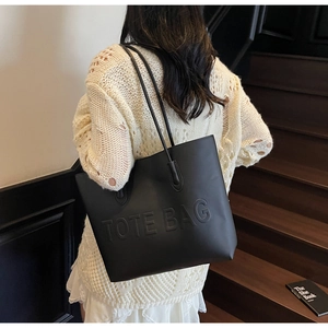 Dettaglio del testo TOTE BAG a rilievo sulla borsa tote nera minimalista in ecopelle