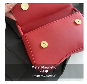 Detail van de gouden magnetische gespen op de rode Saffiano leren crossbodytas