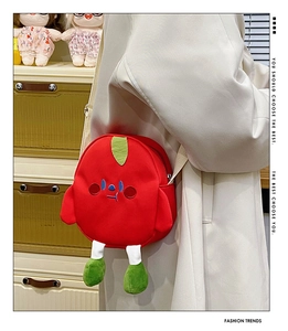 Detail of red cartoon tomato plush crossbody bag with embroidered face and green legs