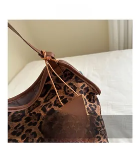Detail of leopard print tote bag with brown leather trim and triangle pouch charm