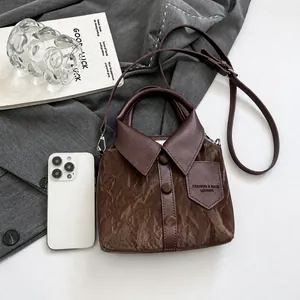 Détail du sac seau créatif en forme de chemise en cuir marron foncé avec référence de taille