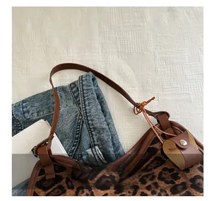 Detailed view of leopard print faux fur texture and brown leather strap on handbag