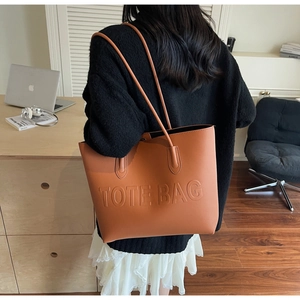 Borsa tote in ecopelle marrone con scritte in rilievo in un ambiente da ufficio