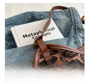 Detail of leopard print handbag with brown leather trim over denim and book background