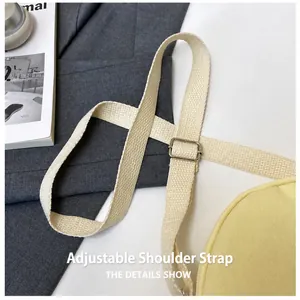 Close-up of yellow fabric bag with adjustable off-white woven strap and silver metal buckle