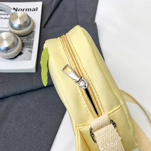 Detailed macro view of the smooth silver metal zipper on a pale yellow canvas crossbody bag