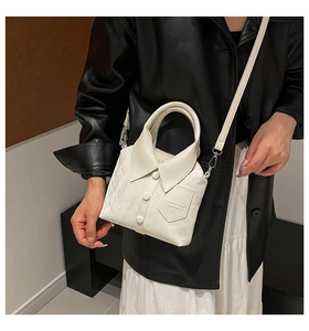 Detail view of a white shirt-shaped crossbody bag featuring a collar and button accents